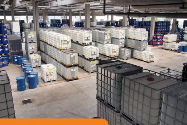 Imagem de depósito de galões com produtos químicos armazenados em pallets de contenção seguindo a NBR 14725 da ABNT.